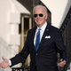 President Joe Biden gestures to journalists after returning to the White House while wearing sunglasses.